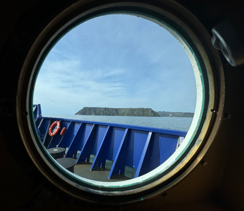 Little Diomede Island viewed through a round ship window.